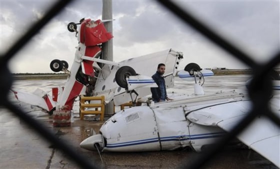 A man checks damaged pilot training planes at the tarmac of Beirut Airport in Lebanon on Saturday. An airport official says a heavy rain storm has seriously damaged four small training planes that were parked on the runway of Beirut's Rafik Hariri airport.